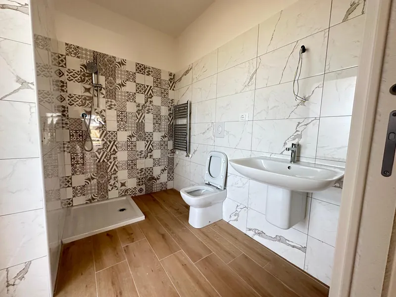 Appartamento consegnato a La Primula: il bagno con doccia e termoarredo — fotografia di ottobre 2026